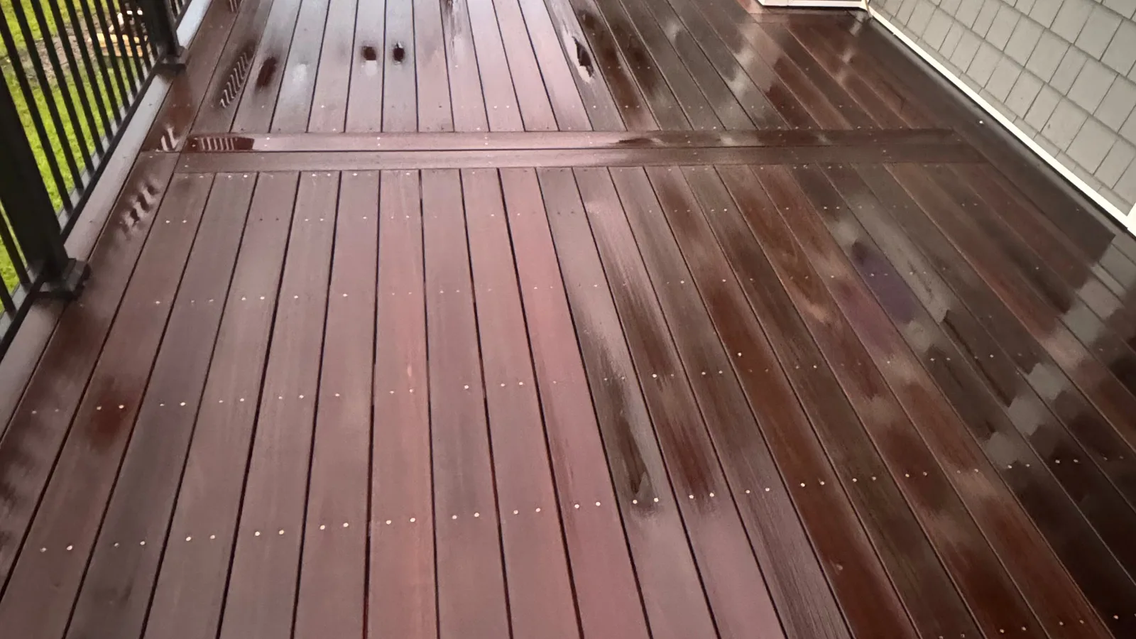 Freshly washed hardwood deck boards and black metal railing at a Jacksonville NC home