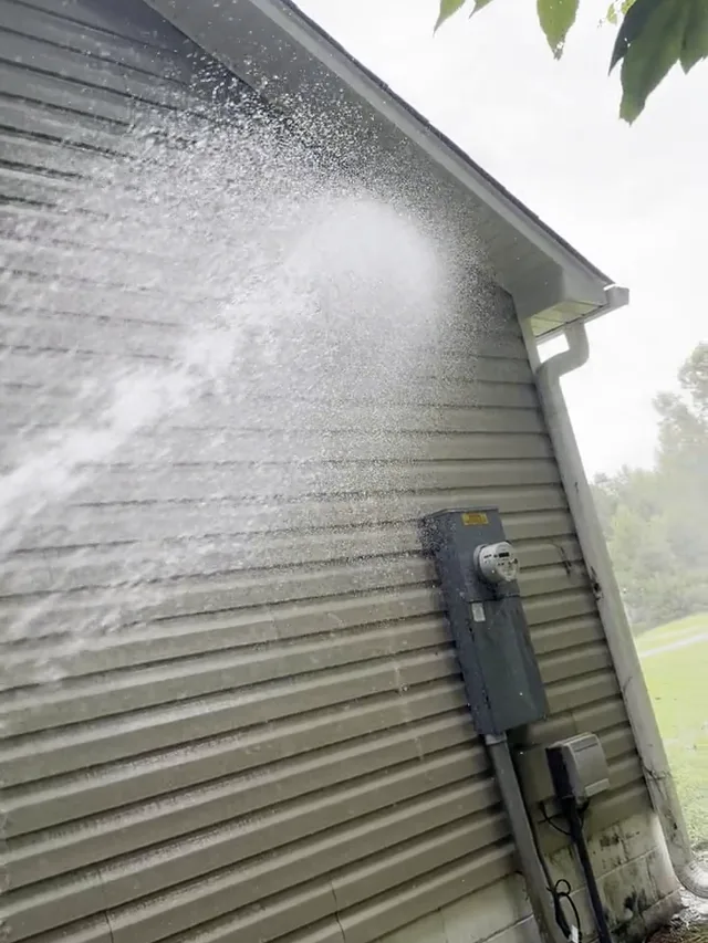 Soft wash foam lifting algae off house siding in Jacksonville NC