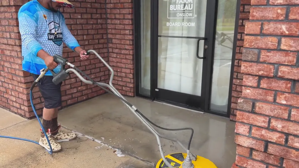 Rotary surface cleaner revealing bright clean concrete against dirty grey concrete