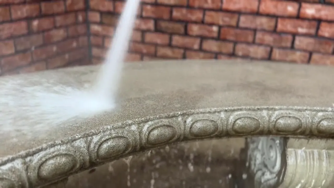 Pressure washer jet lifting algae and debris off carved stone